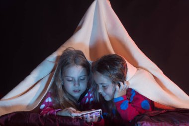 İlgili yüzlü kızlar siyah arka planda battaniyenin altında yatıyor..