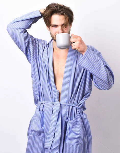 Sexy macho en albornoz sostiene taza y bebe café. — Foto de Stock