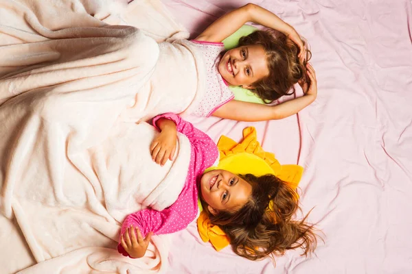 Children with happy faces lie on pink background, top view — Stock Photo, Image