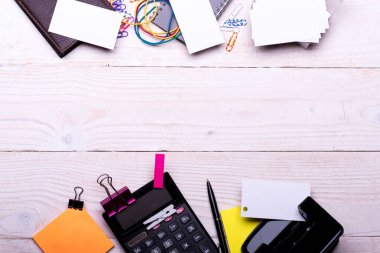 Not defteri, cüzdan, klipsler ve tahta arka plandaki kalemler.