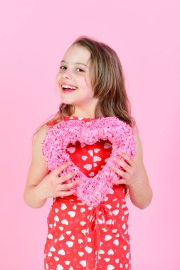 Mutlu kız pembe arka planda pembe kalbi tutuyor.