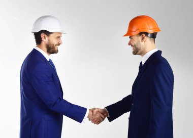 Sakallı ve mutlu yüzlü ortaklar. Kask takan meşgul insanlar kârlı bir anlaşma için tezahürat yapıyor..