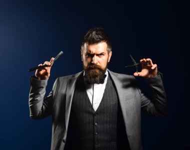 Uzun sakallı adam tıraş bıçağı ve makas tutuyor..