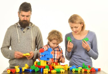 Meşgul yüzlü aile renkli inşaat bloklarından arabalar inşa ediyor.