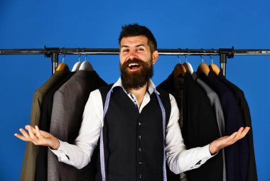 Elbise rafında sakallı bir adam. Resmi kıyafet seçimi.