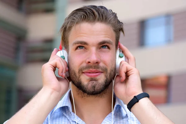Człowiek z nieogoloną twarzą cieszyć się dźwiękiem z nowoczesnych słuchawek. — Zdjęcie stockowe