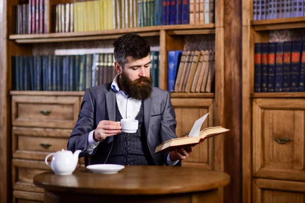 Uomo d'affari si siede in interni vintage, tiene libro e tazza di tè. — Foto Stock