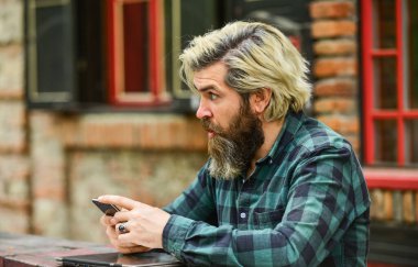 Başvuru konsepti. Sakallı hippi adam akıllı telefon binasının arka planına sahip. Mesaj çevrimiçi. Modern akıllı telefon. İletişim. E-posta gönder. Cevap veriliyor. Şehir kablosuz interneti. Akıllı telefon ayarları