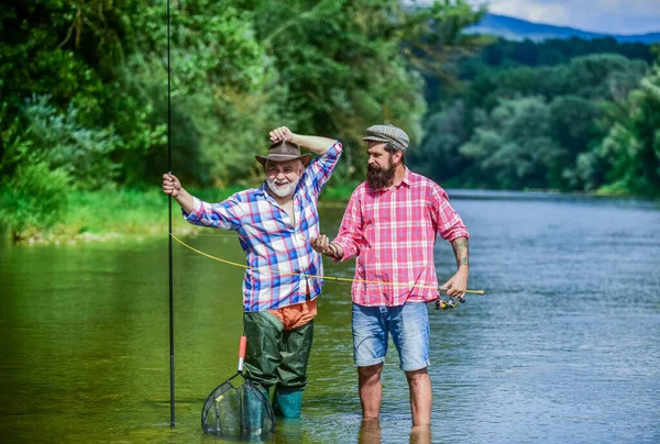 Maestro cebo. Pescador con caña de pescar. Actividad y hobby. Pesca de agua dulce lago estanque río. Hombres barbudos capturando peces. Hombre maduro con amigo pescando. Vacaciones de verano. Gente alegre feliz — Foto de Stock