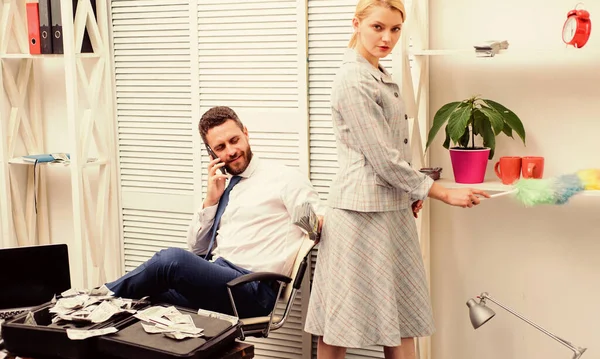 Woman cleaning up office while boss has phone conversation. Gender concept. Gender and career. Personal assistant. Equal rights for education work and salary. Gender discrimination in business life