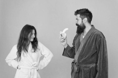 Erotic games for couple. Couple in love blue background. Sensual couple. Sexy woman look at bearded man eating banana. Blowjob and desire. Mens health and potency. Family couple in home clothing