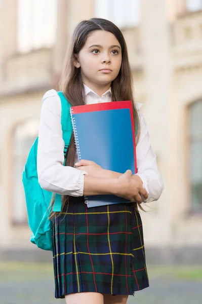 Liten flicka student skoluniform och ryggsäck hålla böcker, läsår koncept — Stockfoto