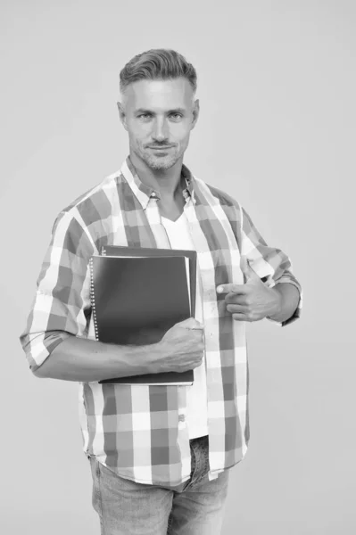 Este é o meu livro. homem tutor apontando dedo caderno de exercícios para a lição. Estudante universitário em fundo amarelo. Jovem alegre segurando livro. usar esta informação para aprender. voltar para a escola — Fotografia de Stock