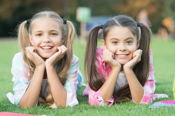 Lindo sonriente niños hermanas relajarse hierba verde, concepto de la infancia feliz — Foto de Stock