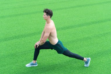 Sağlıklı yaşam ve kendini kontrol kavramı. Genç vatandaş dışarıda egzersiz yapıyor ve yoga yapıyor. Genç sporcu spor salonunda esneme hareketleri yapıyor. İyi esneme hareketleri. Şehir parkında ısınan ve gerinen bir sporcu.