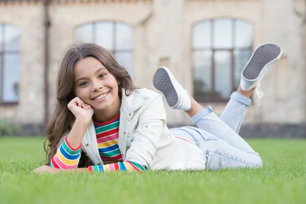 Aranyos mosolygós lány fehér ruhák pihenni zöld fű, boldog gyermekkori koncepció — Stock Fotó