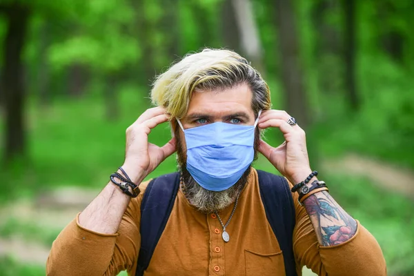 Hipster beschermt tegen luchtverontreiniging of coronavirus. Virusinfectie. De mens geniet van de natuur met gezichtsmasker. Stop infectie. Kom langzaam uit de beperkingen van de vergrendeling. Loop in het park. Vermijd infectie — Stockfoto