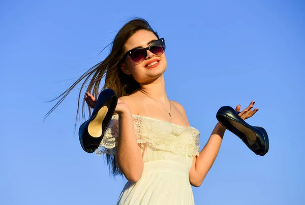 Zomervakantie. Model van een zachte zomerjurk. Vrijheid. Meisje met zonnebril kopieert ruimte. Tegen de zomer. Afterparty concept. Vrouw zonsopgang dragen hoge hakken in de hand. Vrouw op zonnige ochtend blauwe hemel — Stockfoto