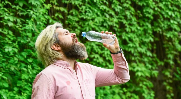 Törstig kille som dricker vatten på flaska. En hälsosam livsstil. Varmt väder. Uppfriskande lemonad. Läskvatten. Vattenbalans. Man skäggig turist dricksvatten plastflaska natur bakgrund. Sommarvärme — Stockfoto