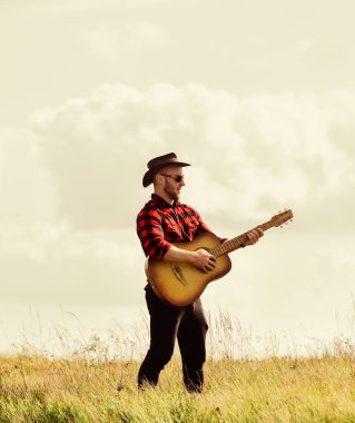 Neşelendirici Eğlence. Country müzik şarkısı. Kareli gömlekli, gitarlı seksi bir adam. Batı kampı ve yürüyüş. Akustik gitaristli kovboy adam. Hipster modası. Mutlu ve özgür