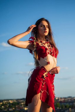 Ezoterizm ve okültizm. Vahşi ve tehlikeli. Ruhsal gelişim. Deri elbiseli bir kadın gökyüzü arka planı. Etnik kabile kavramı. Seksi kızmış. Kabile kıyafetleri. Kabile kültürü. Köklerine geri dön.