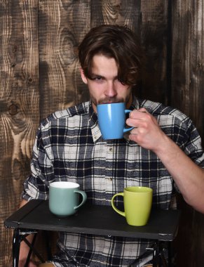 Ahşap arka planda bardakları tutan yakışıklı adam.