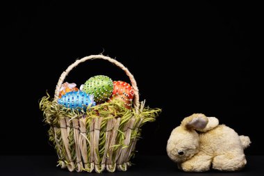 Parlak renkli ipliklerle süslenmiş yumurtalar ve sepette boncuklar.