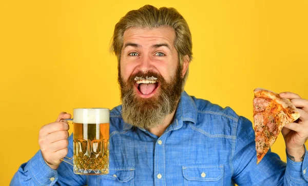 Fast food. homem barbudo feliz com cerveja e pizza. Comida italiana. A itália está aqui. Um tipo no bar a beber cerveja e a comer pizza. Um brinde. um copo de cerveja e pizza. assistir futebol na TV — Fotografia de Stock