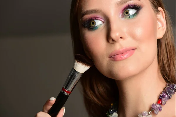 Concetto di moda: ragazza con pennello per il trucco che mette ombretti colorati — Foto Stock