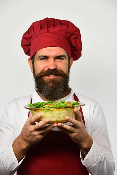 Cook med leende i vinröd uniform håller bakade skålen. — Stockfoto