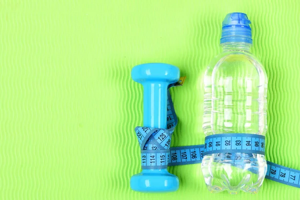 Фитнес гантели, сантиметр и бутылка воды. — стоковое фото