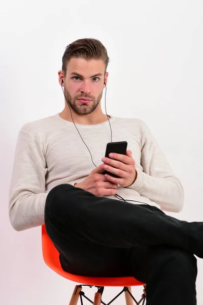 Guy with beard holds MP3 player and wears earphones — Stock Photo, Image