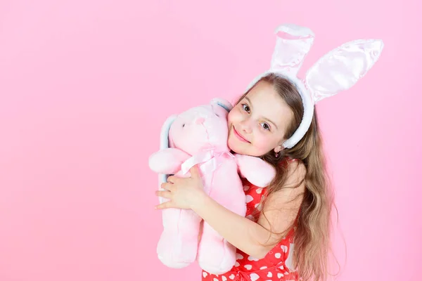 快乐的女孩抱着粉色背景的兔子玩具 — 图库照片