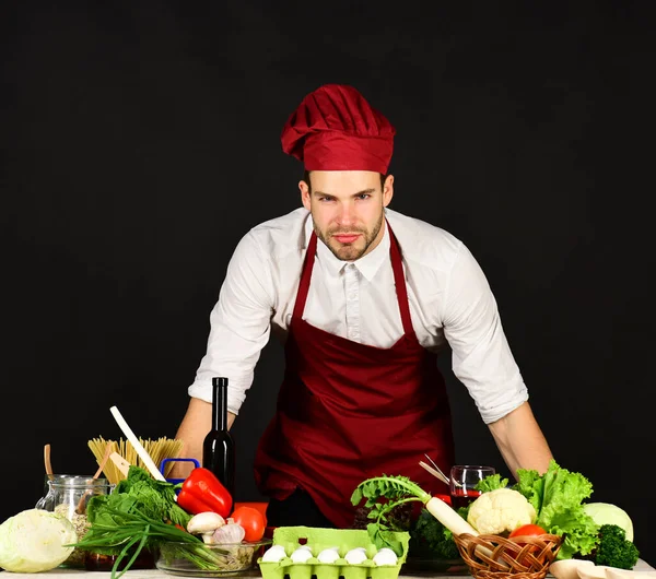 Mann mit weinrotem Hut und Schürze posiert in der Nähe von Lebensmitteln — Stockfoto