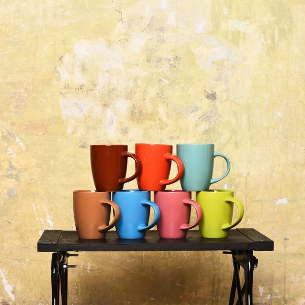 Casa acolhedora e conceito de utensílios de cozinha. Mesa com copos coloridos no fundo da parede . — Fotografia de Stock