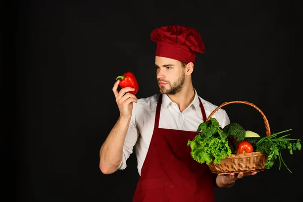 Chef em uniforme de Borgonha mantém a pimenta vermelha na mão . — Fotografia de Stock