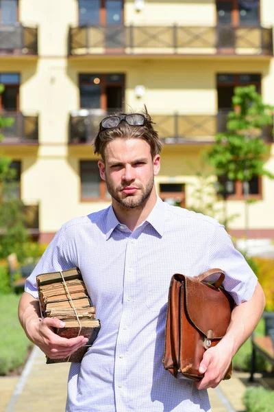Hombre con maletín y pila de libros viejos en el patio —  Fotos de Stock