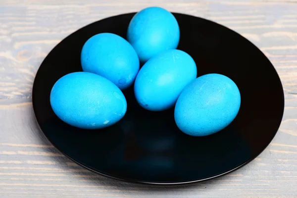 Traditional easter eggs painted in blue color on black plate — Stock Photo, Image