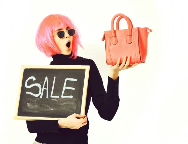 Girl in wig holding bag and board with sale inscription — Stock Photo, Image