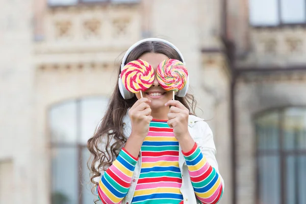 Веселая девушка современные беспроводные наушники едят конфеты, сахарная зависимость концепции — стоковое фото
