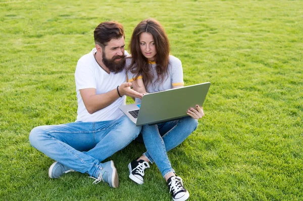 Veselý pár použít notebook sedět zelená tráva, open air office koncept — Stock fotografie
