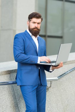 Seçkin ol. Yakışıklı adam pahalı ofis ceketi giyiyor. Çevik iş. Her zaman çevrimiçi ol. Dizüstü bilgisayarı olan kendinden emin bir erkek yönetici. Şirketin başarılı sahibi bilgisayarda çalışıyor.