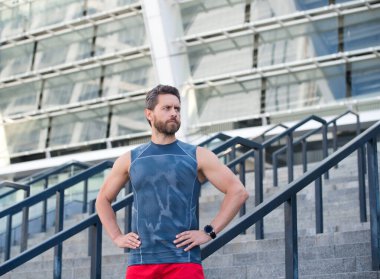 Spor Giysili Adam. Küçük bir mola. Sakallı şehir koşucusu. Spor seansından sonra sakallı sporcu spor sonuçlarını kontrol ediyor. Kronometre özelliği olan dışarıdaki etkinlikler için dijital saat