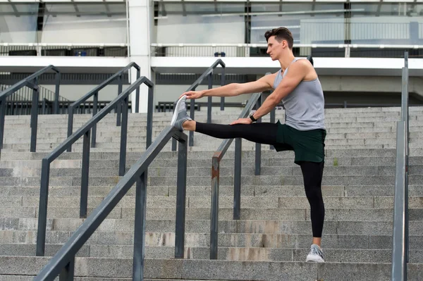 Determinado atleta masculino que estira las piernas al aire libre preparándose para el entrenamiento. Calienta primero. Mantener esos músculos flexibles. Tener un buen estiramiento. Hombre estirándose. Gran calentamiento. — Foto de Stock