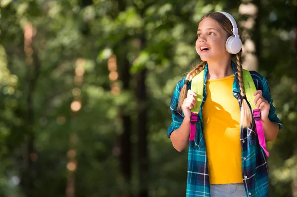 English as second language. Happy child listen to headphones natural outdoors. Language learning courses. Foreign language school. New technology. Private teaching. Summer vacation, copy space