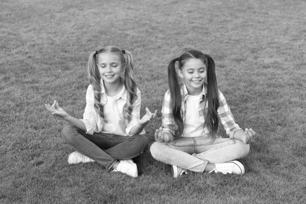 Practicar mudras durante la meditación. Los niños felices hacen meditación sobre hierba verde. Las niñas pequeñas disfrutan la práctica de meditación. Meditación y mantra. Medita para concentrarte. Zen y la iluminación —  Fotos de Stock