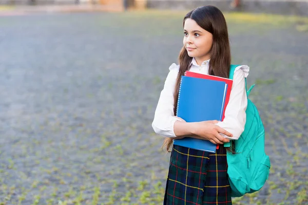 Liten flicka formell stil uniform och ryggsäck hålla böcker, skolan lektioner koncept — Stockfoto