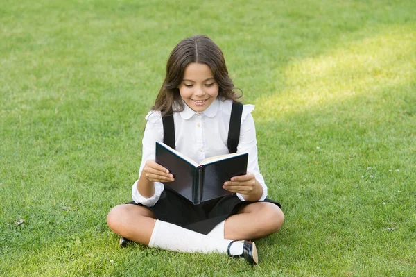 Gelukkig kleuter meisje met boek op schoolplein. terug naar school. hardwerkende kind met boek. begrip onderwijs en lezen. ontwikkeling van de verbeelding. schattig meisje lees boek — Stockfoto