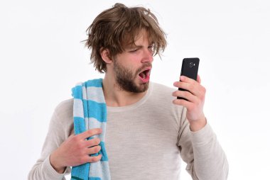 Uykulu suratlı bir adam akıllı telefonuna bakar.