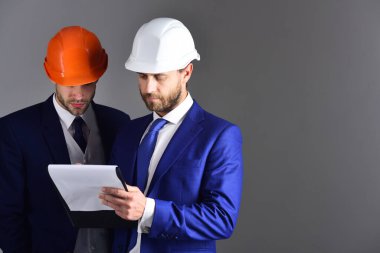 Ciddi yüzleri olan mimarlar projeyi tartışıyor. Girişimci ve mimar inşaat planına bakın.